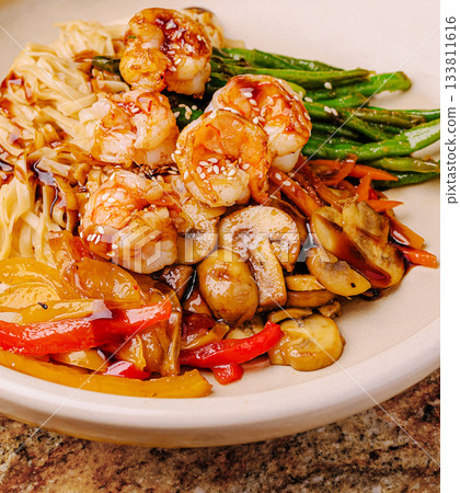 Shrimp stir fry with noodles and vegetables served on a plate 133811616