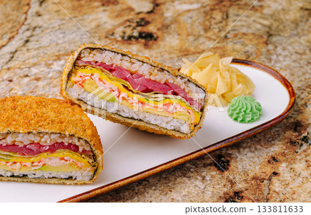 Sushi sandwich sliced revealing colorful layers of fish and vegetables Sushi sandwich sliced revealing colorful layers of fish and vegetables 133811633