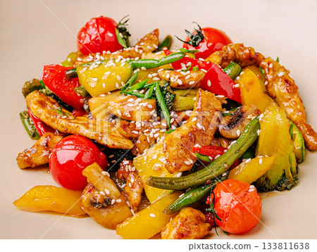 Colorful stir-fried vegetables and chicken served on a beige plate Colorful stir-fried vegetables and chicken served on a beige plate 133811638