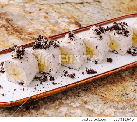 Delicious dessert with rolled ice cream and banana served on a plate Delicious dessert with rolled ice cream and banana served on a plate 133811640