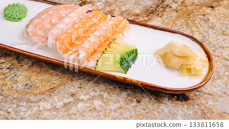 Sushi platter featuring shrimp, cucumber, and wasabi on a decorative plate Sushi platter featuring shrimp, cucumber, and wasabi on a decorative plate 133811658