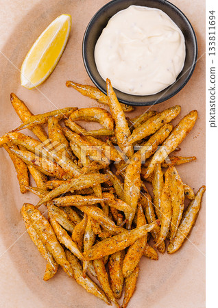 Crispy fried fish served with lemon and dip on a plate 133811694