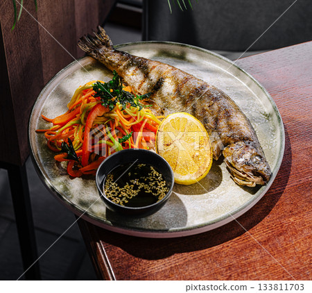 Delicious grilled fish served with fresh vegetables and sauce 133811703