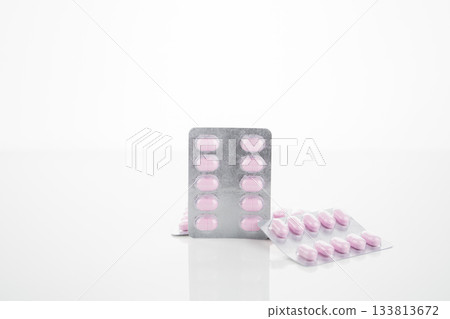 Pink oral tablet pill packaged in blister pack isolated on white background symbolizing pharmaceutical product prescription drug healthcare and medicine industry for therapy treatment and research. 133813672