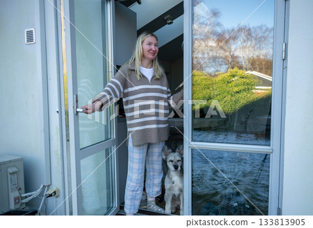 woman standing in doorway with dog on winter morning 133813905