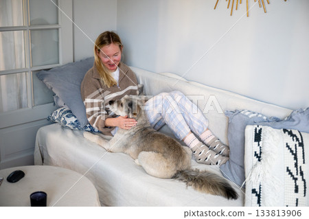 woman relaxing on sofa with friendly dog at home woman relaxing on sofa with friendly dog at home 133813906