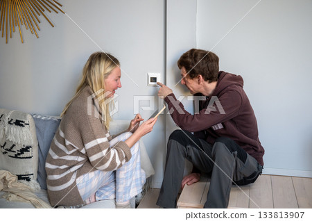 couple adjusting home thermostat together couple adjusting home thermostat together 133813907