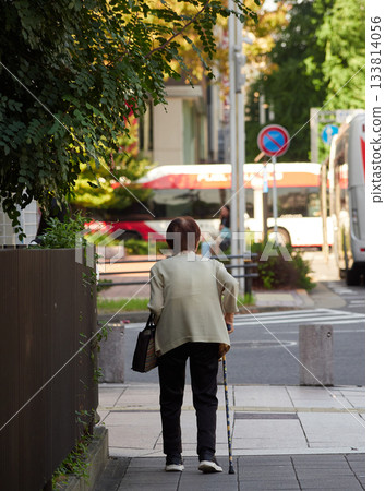 Senior woman walking in a busy street in summer 133814056