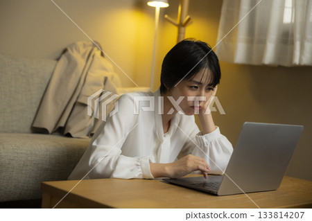 A woman operating a computer in her room at night 133814207