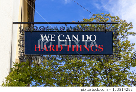 Support, help we can do hard things symbol. Concept words We can do hard things on black beautiful road sign. Beautiful blue sky trees background. Business we can do hard things concept. Copy space. Support, help we can do hard things symbol. Concept words We can do hard things on black beautiful road sign. Beautiful blue sky trees background. Business we can do hard things concept. Copy space. 133814292