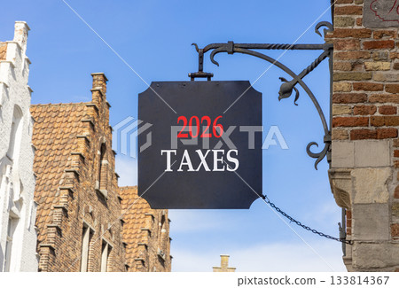 2026 taxes new year symbol. Concept words 2026 taxes on beautiful black road sign. Beautiful street and buildings in Brugge blue sky background. Business and 2026 taxes new year concept. Copy space. 2026 taxes new year symbol. Concept words 2026 taxes on beautiful black road sign. Beautiful street and buildings in Brugge blue sky background. Business and 2026 taxes new year concept. Copy space. 133814367