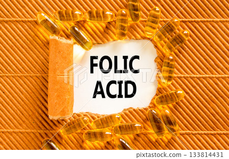 Folic acid symbol. Concept words Folic acid on beautiful white paper. Yellow pills tablets. Beautiful brown background. Medical healthy lifestyle folic acid concept. 133814431