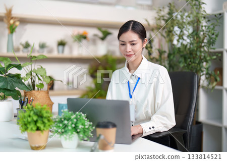 Focused woman working on laptop in stylish office 133814521