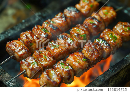 Juicy pieces of meat skewer grilling over hot flames create a delicious aroma at a backyard barbecue on a sunny day Juicy pieces of meat skewer grilling over hot flames create a delicious aroma at a backyard barbecue on a sunny day 133814715