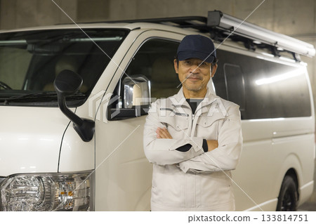 一名工人站在一輛車旁。 133814751