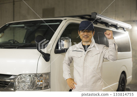 一名工人站在一輛車旁。 一名工人站在一輛車旁。 133814755