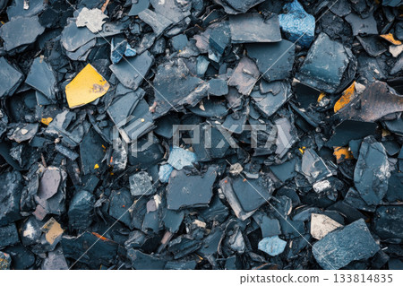 Small fragments of black, blue, and yellow materials are scattered in an industrial area, showcasing various textures and colors Small fragments of black, blue, and yellow materials are scattered in an industrial area, showcasing various textures and colors 133814835