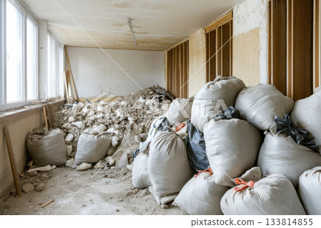 Renovation work is in progress with bags of construction debris stacked inside a partially finished room Renovation work is in progress with bags of construction debris stacked inside a partially finished room 133814855