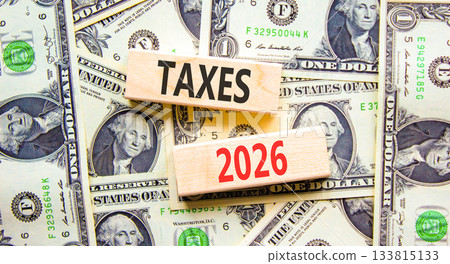 Taxes 2026 new year symbol. Concept words Taxes 2026 on beautiful wooden blocks. Beautiful dollar bills background. Dollar bills. Business and taxes 2026 new year concept. Copy space. 133815133