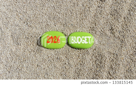 2026 Budget symbol. Concept words 2026 Budget on beautiful green stones on sand beach. Beautiful sand beach background. Business and 2026 budget concept. Copy space. 2026 Budget symbol. Concept words 2026 Budget on beautiful green stones on sand beach. Beautiful sand beach background. Business and 2026 budget concept. Copy space. 133815145
