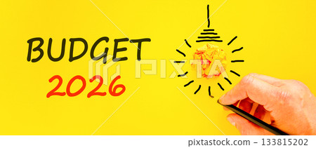 Budget 2026 symbol. Concept words Budget 2026 on beautiful yellow paper. Beautiful orange paper background. Light bulb icon. Businessman's hand with pen. Business and budget 2026 concept. Copy space. Budget 2026 symbol. Concept words Budget 2026 on beautiful yellow paper. Beautiful orange paper background. Light bulb icon. Businessman's hand with pen. Business and budget 2026 concept. Copy space. 133815202