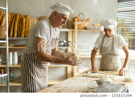 Elderly man and woman kneading and rolling out dough Elderly man and woman kneading and rolling out dough 133815264