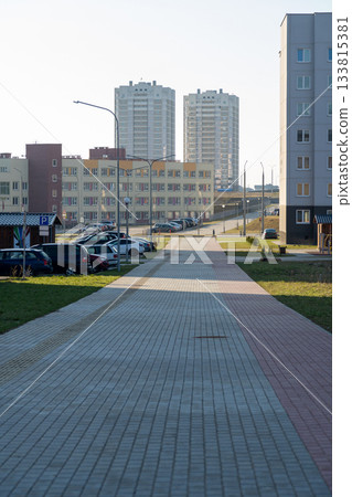A modern urban residential area featuring apartment complexes and a paved walkway A modern urban residential area featuring apartment complexes and a paved walkway 133815381