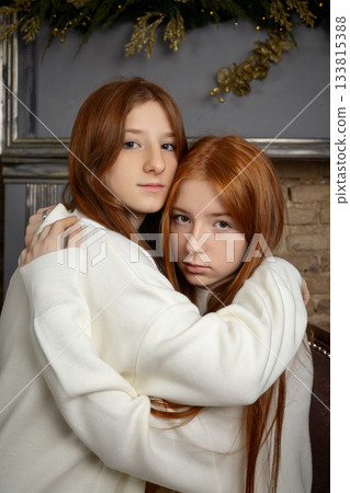 Two young women with long red hair wearing white Christmas sweaters Two young women with long red hair wearing white Christmas sweaters 133815388