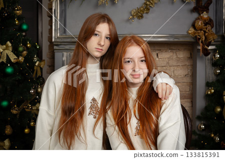 Two young women with long red hair wearing white Christmas sweaters Two young women with long red hair wearing white Christmas sweaters 133815391
