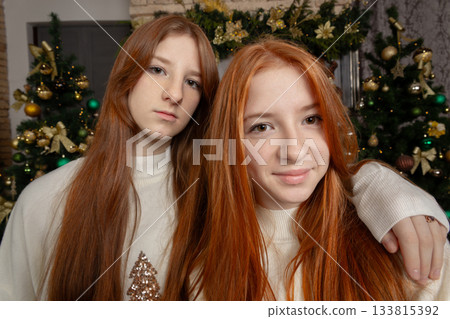 Two young women with long red hair wearing white Christmas sweaters 133815392