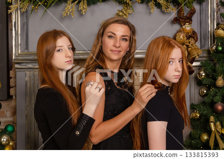 A family portrait featuring a mother and her two daughters, who have long red hair 133815393
