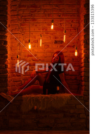 A young woman with red hair poses in moody, industrial lighting A young woman with red hair poses in moody, industrial lighting 133815396