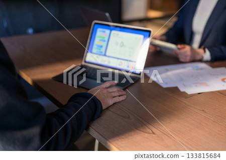 Business people meeting at a conference room table with laptops and documents Business people meeting at a conference room table with laptops and documents 133815684