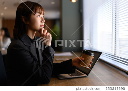 女商人端著咖啡凝視窗外 133815690