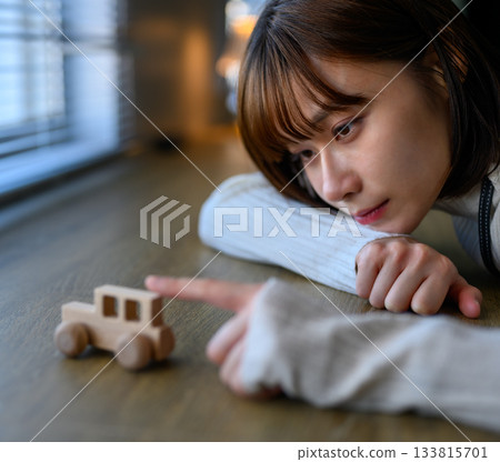 Close-up of a young woman looking at a toy wooden car 133815701