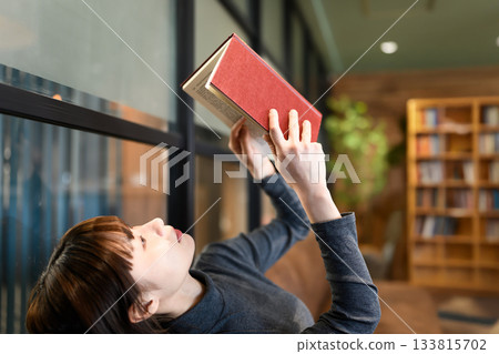 Young woman reading a book while relaxing in a cafe 133815702