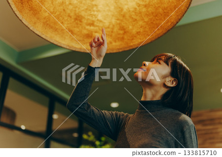 年輕女子抬頭望著燈光 133815710