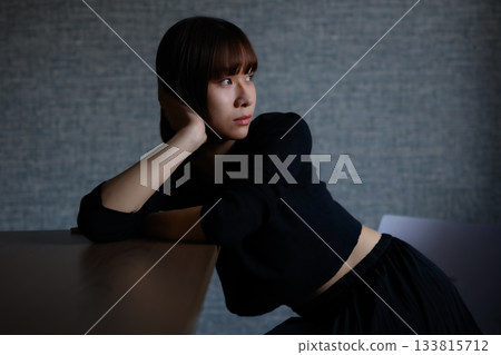 沉思的年輕女子,雙手手肘撐在桌上。 沉思的年輕女子,雙手手肘撐在桌上。 133815712