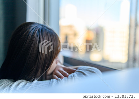 Profile of a young woman gazing at the city from a window Profile of a young woman gazing at the city from a window 133815723