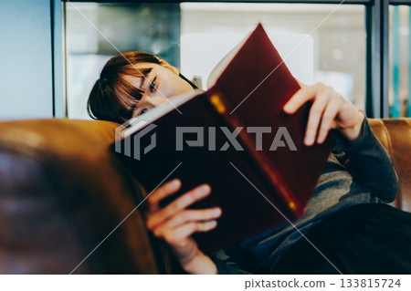 年輕女子在皮沙發上看書 133815724