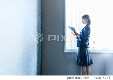 A young businesswoman reading documents by the window 133815741