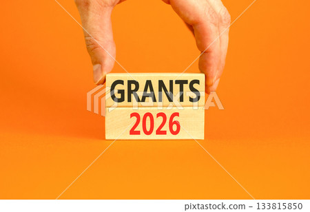 Grants 2026 symbol. Concept words Grants 2026 on beautiful wooden blocks. Beautiful orange paper background. Businessman's hand. Business and grants 2026 concept. Copy space. 133815850