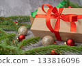 Christmas composition. Gift box, fir tree branches, red and gold decorations on grey background. High quality photo 133816096