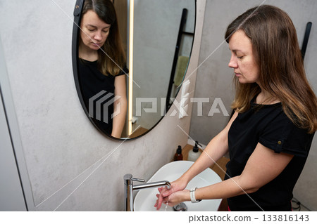 Woman doing morning hygiene routine in a bathroom Woman doing morning hygiene routine in a bathroom 133816143