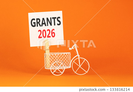 Grants 2026 symbol. Concept words Grants 2026 on beautiful white paper on wooden clothespin. Beautiful orange background. Beautiful miniature bicycle. Business and grants 2026 concept. Copy space. 133816214