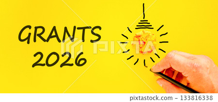 Grants 2026 symbol. Concept words Grants 2026 on beautiful yellow paper. Beautiful orange paper background. Light bulb icon. Businessman's hand with pen. Business and grants 2026 concept. Copy space. Grants 2026 symbol. Concept words Grants 2026 on beautiful yellow paper. Beautiful orange paper background. Light bulb icon. Businessman's hand with pen. Business and grants 2026 concept. Copy space. 133816338
