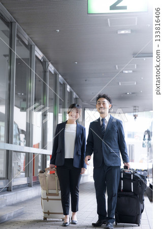 Smiling office worker pulling a suitcase on a business trip, full body Smiling office worker pulling a suitcase on a business trip, full body 133816406