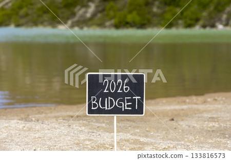 2026 Budget symbol. Concept words 2026 Budget on beautiful black blackboard. Beautiful mountain lake sand beach background. Business and 2026 budget concept. Copy space. 2026 Budget symbol. Concept words 2026 Budget on beautiful black blackboard. Beautiful mountain lake sand beach background. Business and 2026 budget concept. Copy space. 133816573