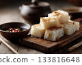 Slices of steamed turnip cake on a wooden board, soy dipping sauce nearby, simple Cantonese New Year atmosphere 133816648