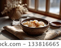 Warm bowl of tteokguk with sliced rice cakes and garnish, Korean New Year table 133816665